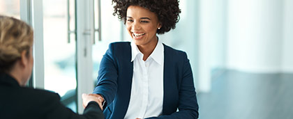 smiling woman in a suit shakes hands with another